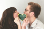 Kissing behind a Greenheart Travel sticker.