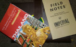 A Thailand guidebook, a Greenheart Travel sticker and a notebook.
